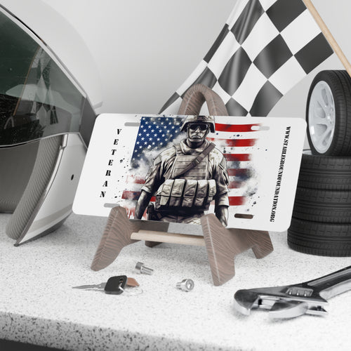 White vanity license plate featuring a soldier in tactical gear with the American flag in the background and “Veteran” text.