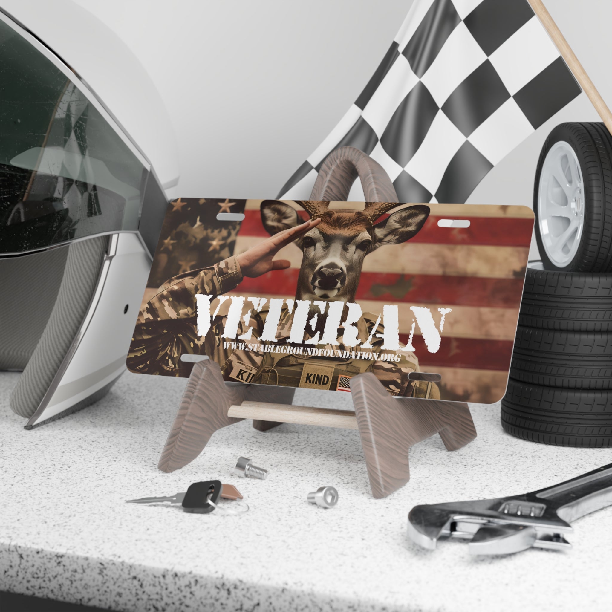 Funny patriotic license plate with deer in military uniform saluting in front of American flag background featuring the word veteran.