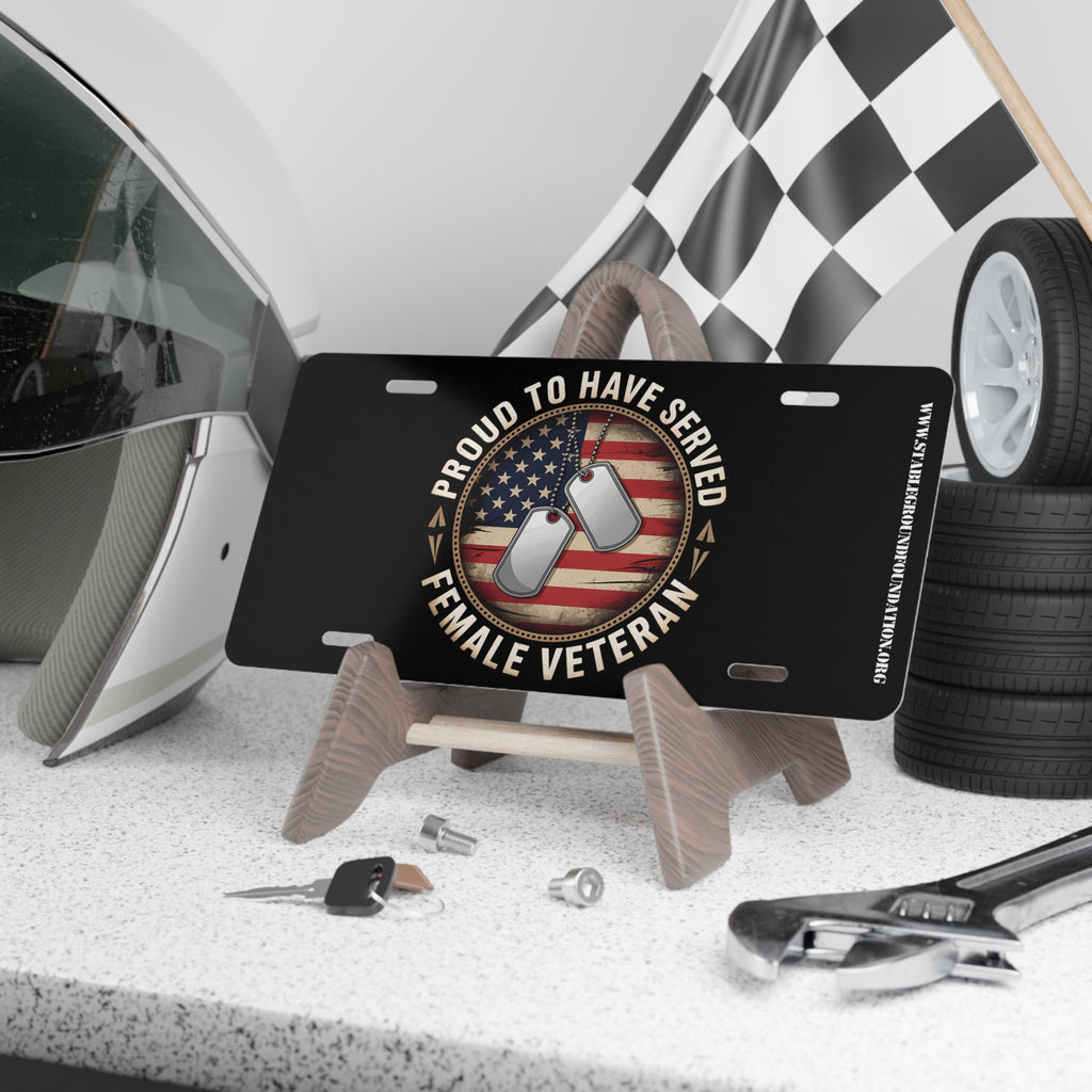 Black license plate with American flag background, dog tags, and text “Proud to Have Served – Female Veteran.”