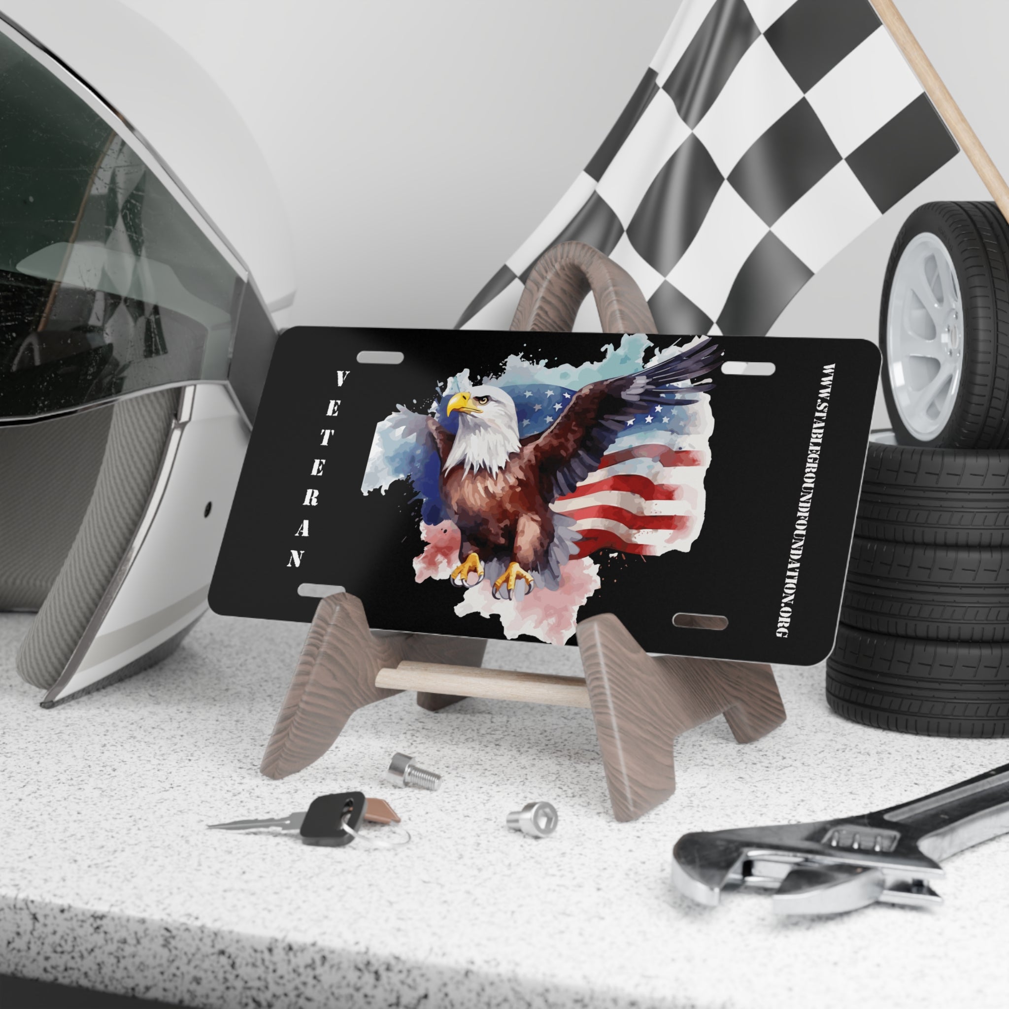 Black license plate featuring a bold bald eagle soaring in front of a waving American flag with the word “Veteran” in white text along the side.